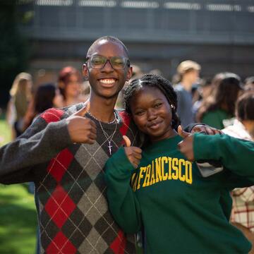 Two students giving a thumbs up and smiling