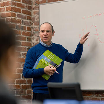professor points at whiteboard in class