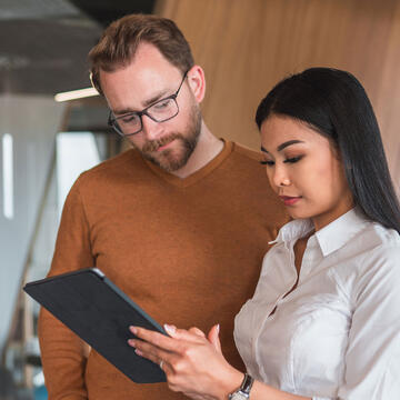 Two students look at a tablet device.