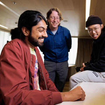 Three people look at a computer