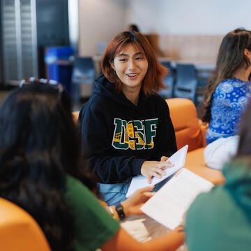 Student chatting with peers, holding a notebook