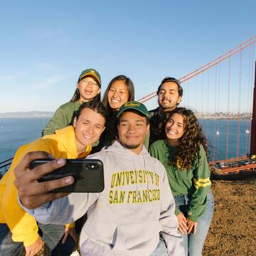 student taking a selfie on a bluff overlooking the golden gate bridge