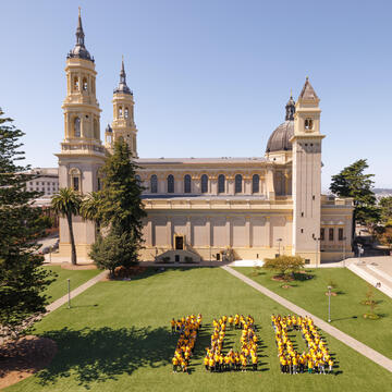 St. Ignatius Church with students shaped in a 100 on Welch Field