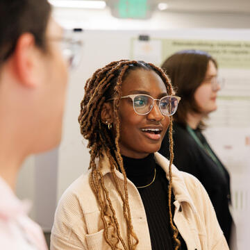 student with glasses looks away while smiling