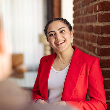 School of Management student in a red blazer chatting in a professional setting