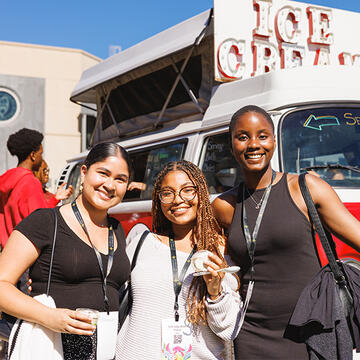 Three students holding up ice cream and smiling at a USF event
