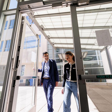 Professor and law student entering USF law building, smiling
