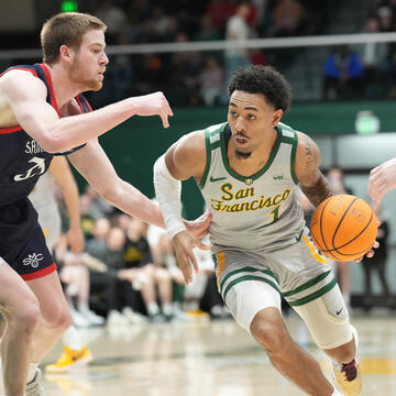 Basketball player dribbles around defender