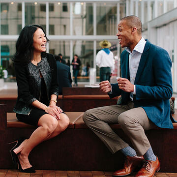 Two business professionals setting on a bench, chatting
