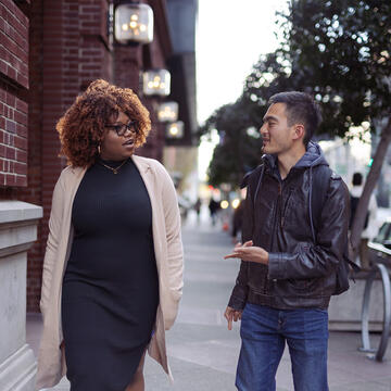 Two people walking and talking on a city sidewalk