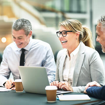 Corporate workers smiling in front of laptops
