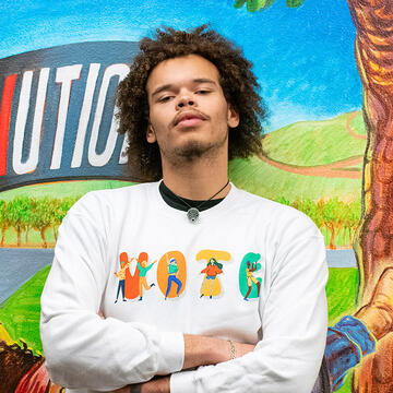 student stands in front of mccarthy center mural