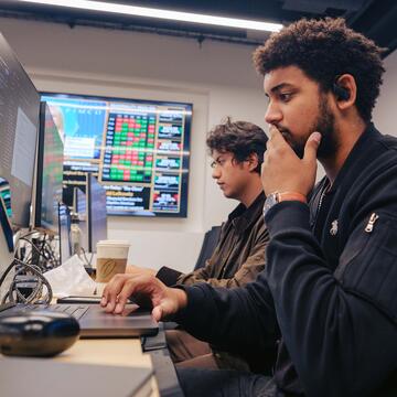 Two students work on computers in the investment lab.