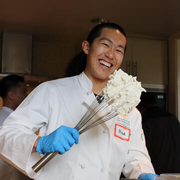 student holds up cooking utensil