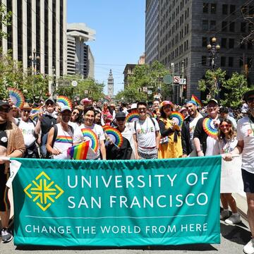 Group of people holding the University of San Francisco banner and marching in the Pride parade
