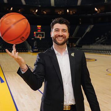 Sport management student in business attire spinning basketball on finger