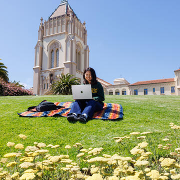 student uses laptop on lawn