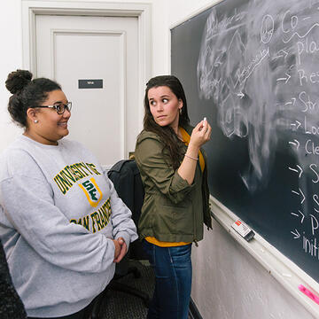 students writes on chalkboard