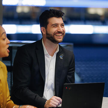 Sport management student smiling at a table with peers in Chase Center