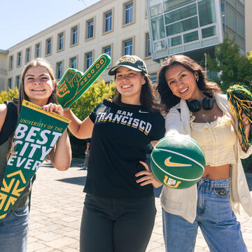 Students hold USF branded banners and foam fingers on first day of class