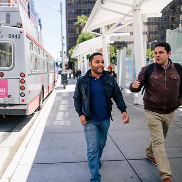 Two people walking near a bus stop