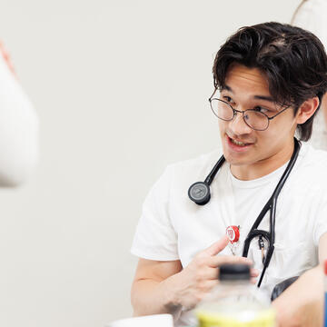 Nursing student with stethoscope talking to event attendee during a campus health fair