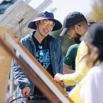 Student wearing safety glasses standing next to solar panels