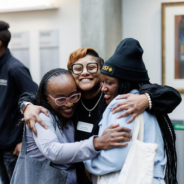 Three students hugging and smiling