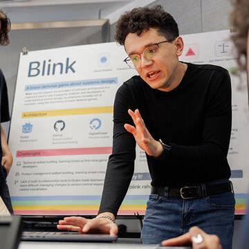 Student demonstrates in front of a presentation board titled Blink