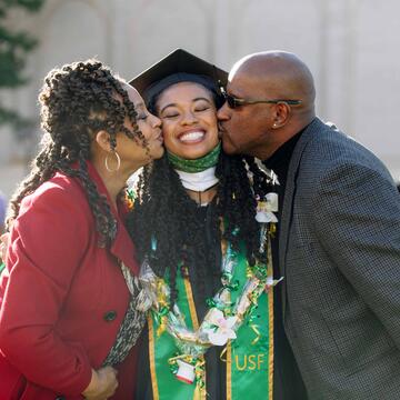 Parents kissing new graduate on the cheeks