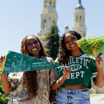 USF students hold pom-pom and sign with USF logo and colors