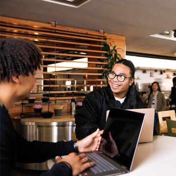 Students hanging out in the school cafeteria, working on laptops