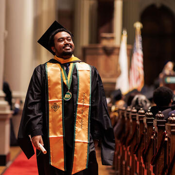 Student smiling and walking the isle at graduation