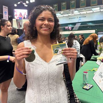 Carolayne Lange smiling and holding up USF swag