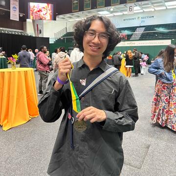 Jacob Eusebio smiling and holding a USF Presidents Ambassador medal