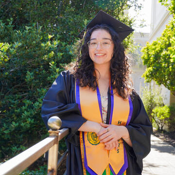 Student in graduate regalia poses for portrait