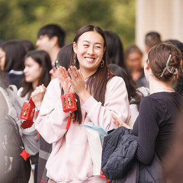 student claps while holding onto a red cultural lantern