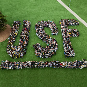 Students pose together to make a USF logo