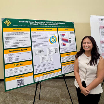 student stands in front of research board during an event