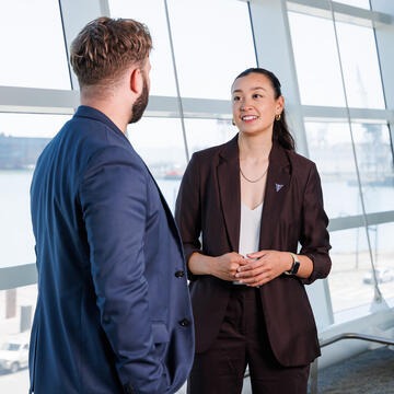 sport management students talk in front of window