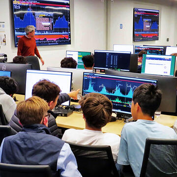 students point at screens with charts
