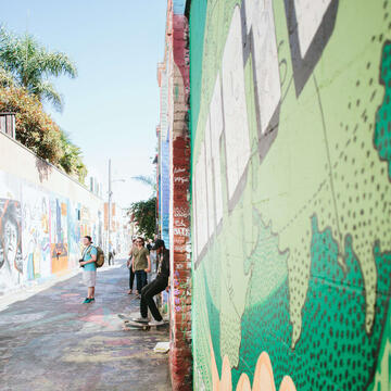 Students taking photos of graffiti art in an alley