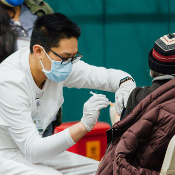 Norman Feng gives vaccination to patient.