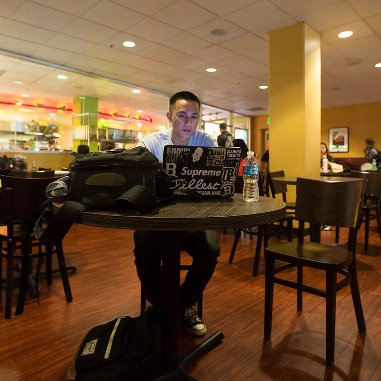 A student studies on a laptop in a cafe.