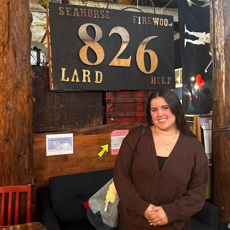 student stands in front of 826 sign