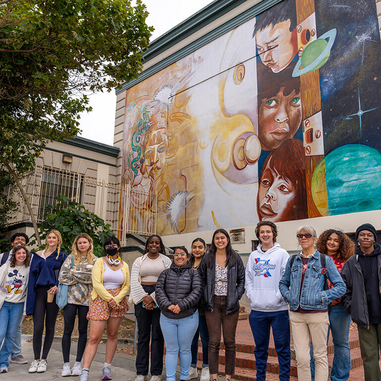 group of students standing in front of a mural in the Mission neighborhood of San Francisco
