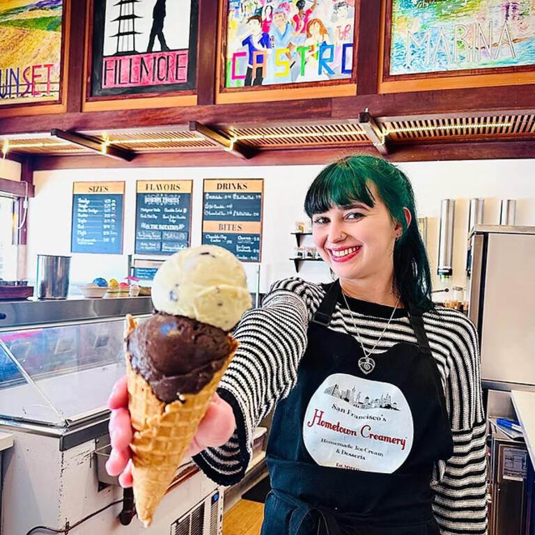 San Francisco’s Hometown Creamery worker smiling and holding up a ice cream cone