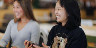Student smiles in class while holding a phone.