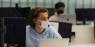 Student with a laptop looks to the side while listening in a computer lap