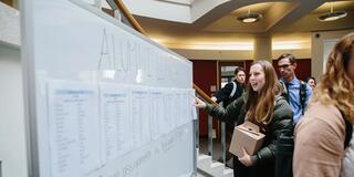 Person stands in front of white board and points